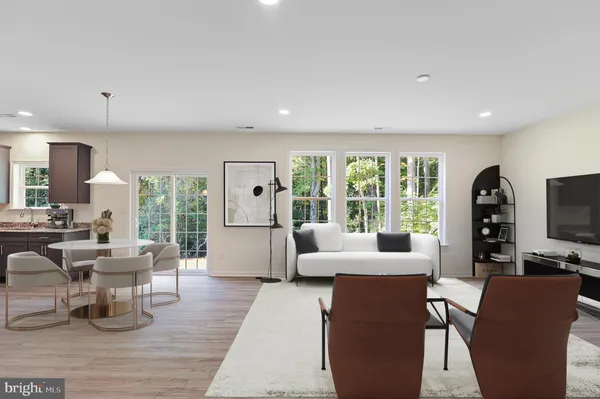 a living room with furniture large windows and wooden floor