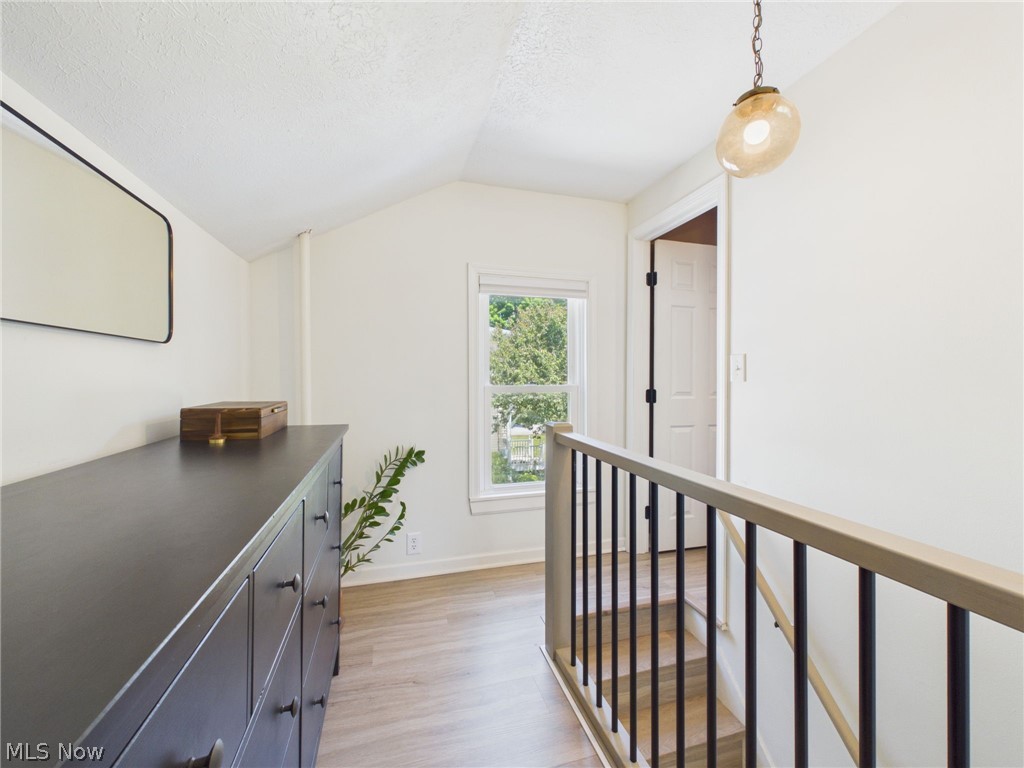 3490 County Line Road Madison, OH 44057 - Photo 11 of 42 Upper landing featuring light wood-finish flooring, white walls, a window with exterior views, and a contemporary pendant light fixture