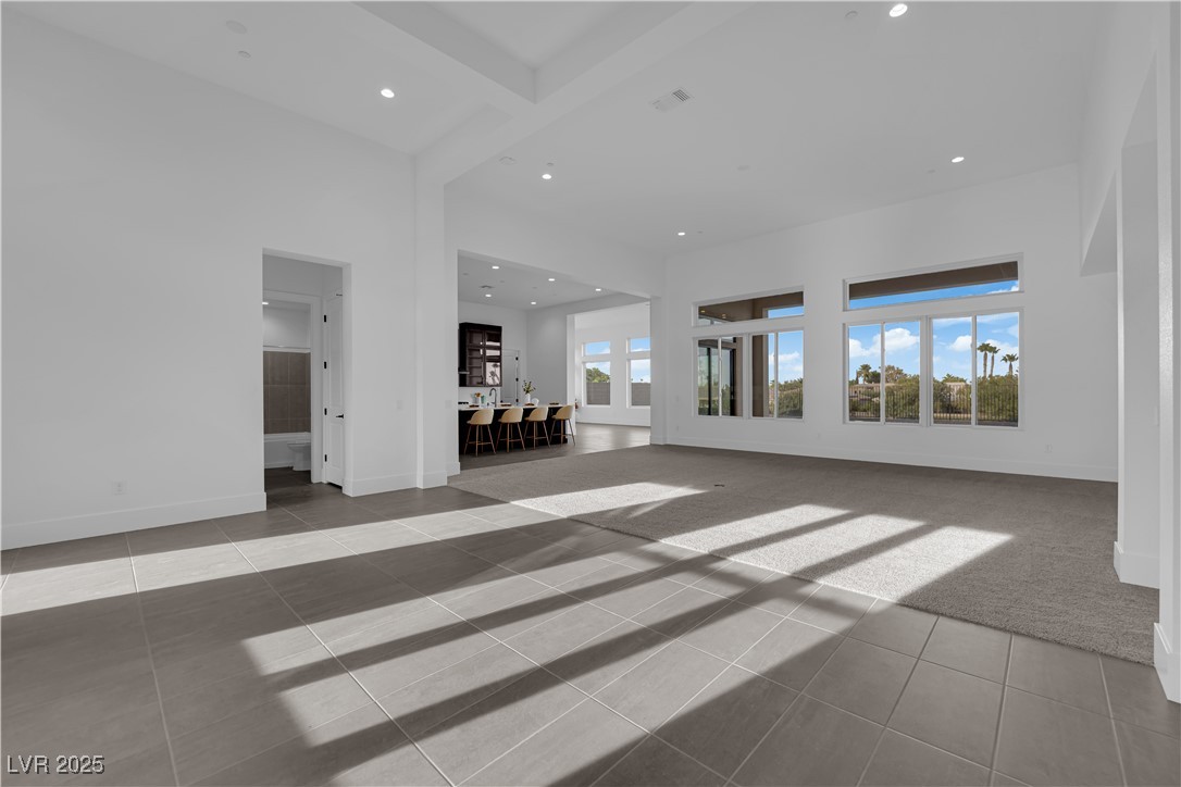 4792 Outlook Peak Street Las Vegas, NV 89135 - Photo 11 of 56 Unfurnished living room featuring beamed ceiling, light tile patterned floors, recessed lighting, and a high ceiling