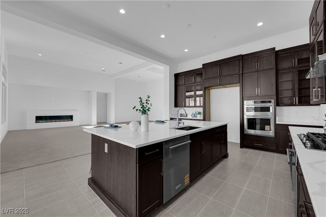 4792 Outlook Peak Street Las Vegas, NV 89135 - Photo 14 of 56 Kitchen featuring dark brown cabinets, recessed lighting, a glass covered fireplace, and light tile patterned floors