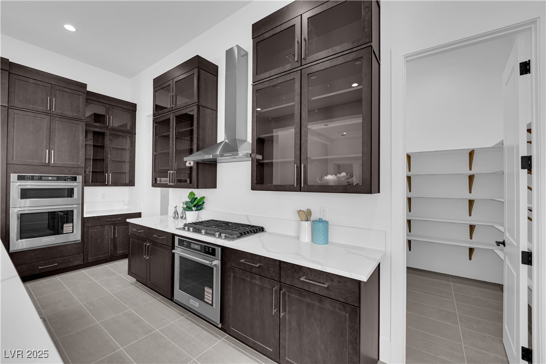 4792 Outlook Peak Street Las Vegas, NV 89135 - Photo 15 of 56 Kitchen with wall chimney exhaust hood, dark brown cabinets, light tile patterned floors, and recessed lighting