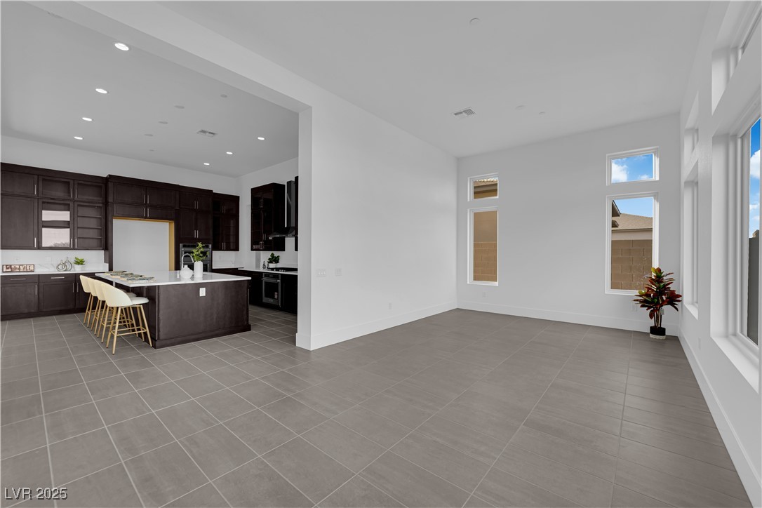 4792 Outlook Peak Street Las Vegas, NV 89135 - Photo 18 of 56 Kitchen featuring a kitchen bar, dark brown cabinetry, a center island, light tile patterned floors, and recessed lighting