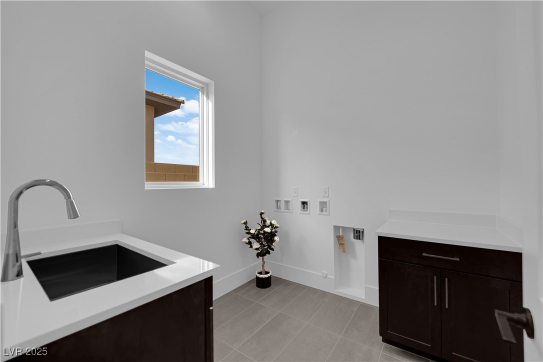 4792 Outlook Peak Street Las Vegas, NV 89135 - Photo 20 of 56 Laundry room featuring cabinet space, washer hookup, light tile patterned floors, and hookup for a gas dryer