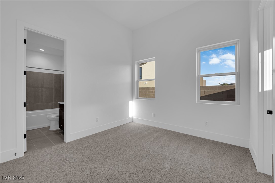 4792 Outlook Peak Street Las Vegas, NV 89135 - Photo 37 of 56 Unfurnished bedroom with light colored carpet, light tile patterned floors, and ensuite bathroom