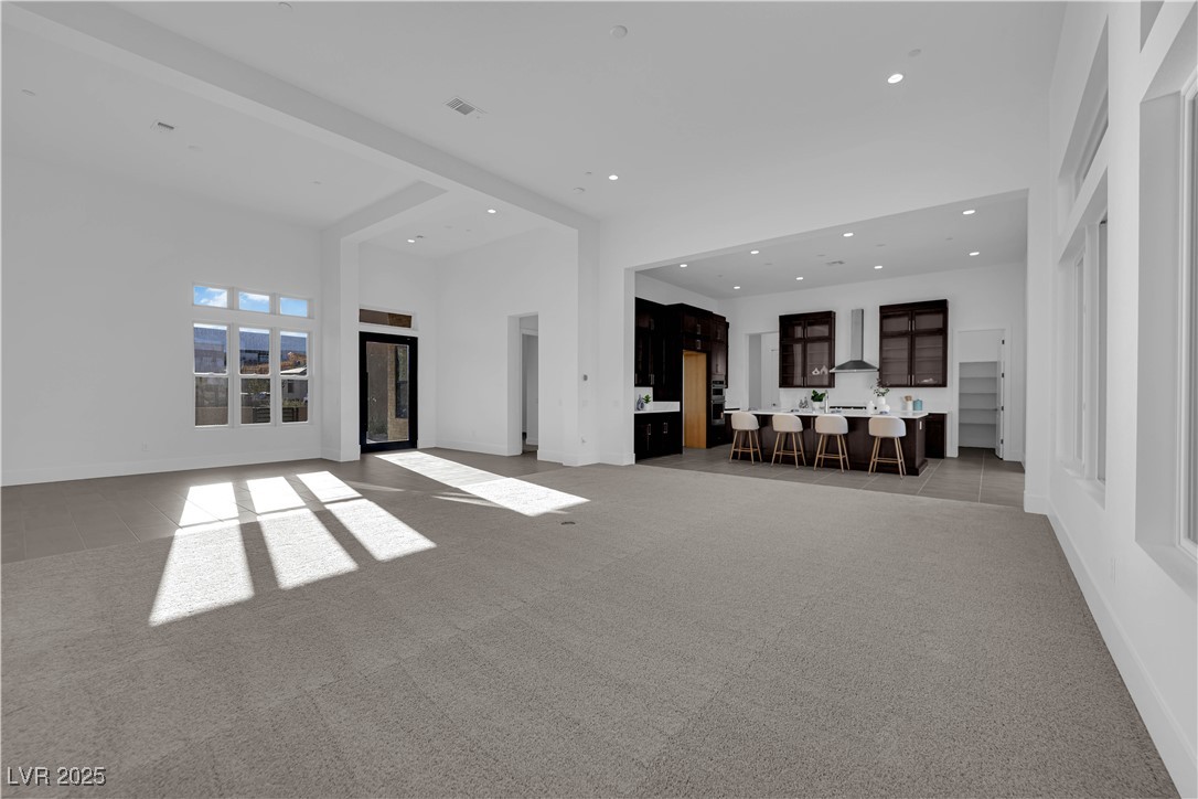 4792 Outlook Peak Street Las Vegas, NV 89135 - Photo 5 of 56 Unfurnished living room featuring light carpet, recessed lighting, and a towering ceiling
