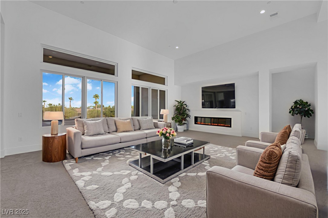 4792 Outlook Peak Street Las Vegas, NV 89135 - Photo 8 of 56 Living area featuring carpet, a glass covered fireplace, a high ceiling, and recessed lighting