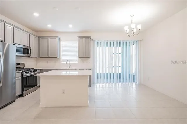 a kitchen with stainless steel appliances granite countertop a stove top oven a sink and a refrigerator