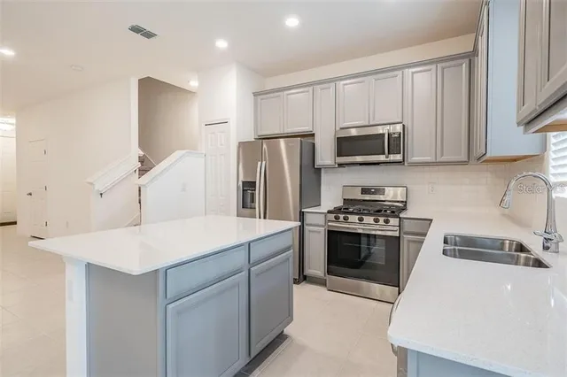 a kitchen with kitchen island a sink stove and refrigerator