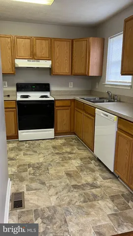 a kitchen with granite countertop a stove top oven sink and cabinets