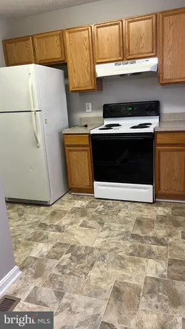 a kitchen with granite countertop a stove and a white refrigerator
