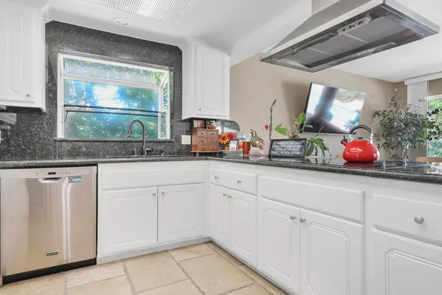 a kitchen with white cabinets and sink
