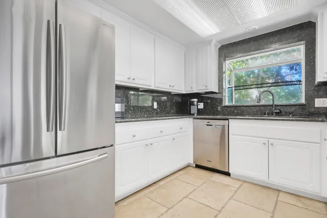 a kitchen with stainless steel appliances granite countertop white cabinets and window