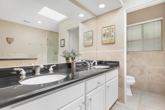 a bathroom with a granite countertop sink mirror and toilet