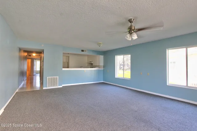 an empty room with windows and ceiling fan
