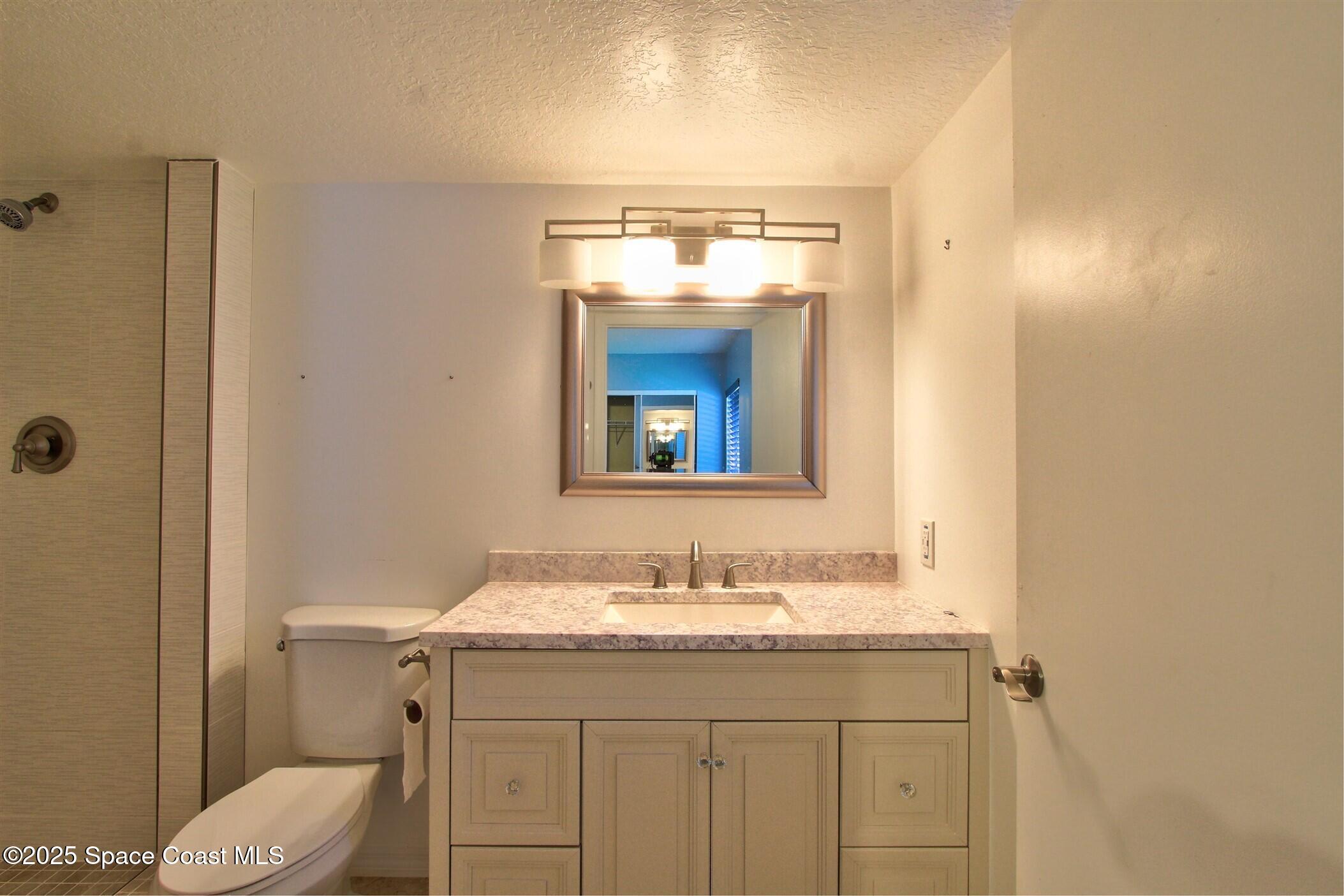 1420 Huntington Lane, Unit 2101 Rockledge, FL 32955 - Photo 18 of 38 a bathroom with a granite countertop sink toilet and mirror