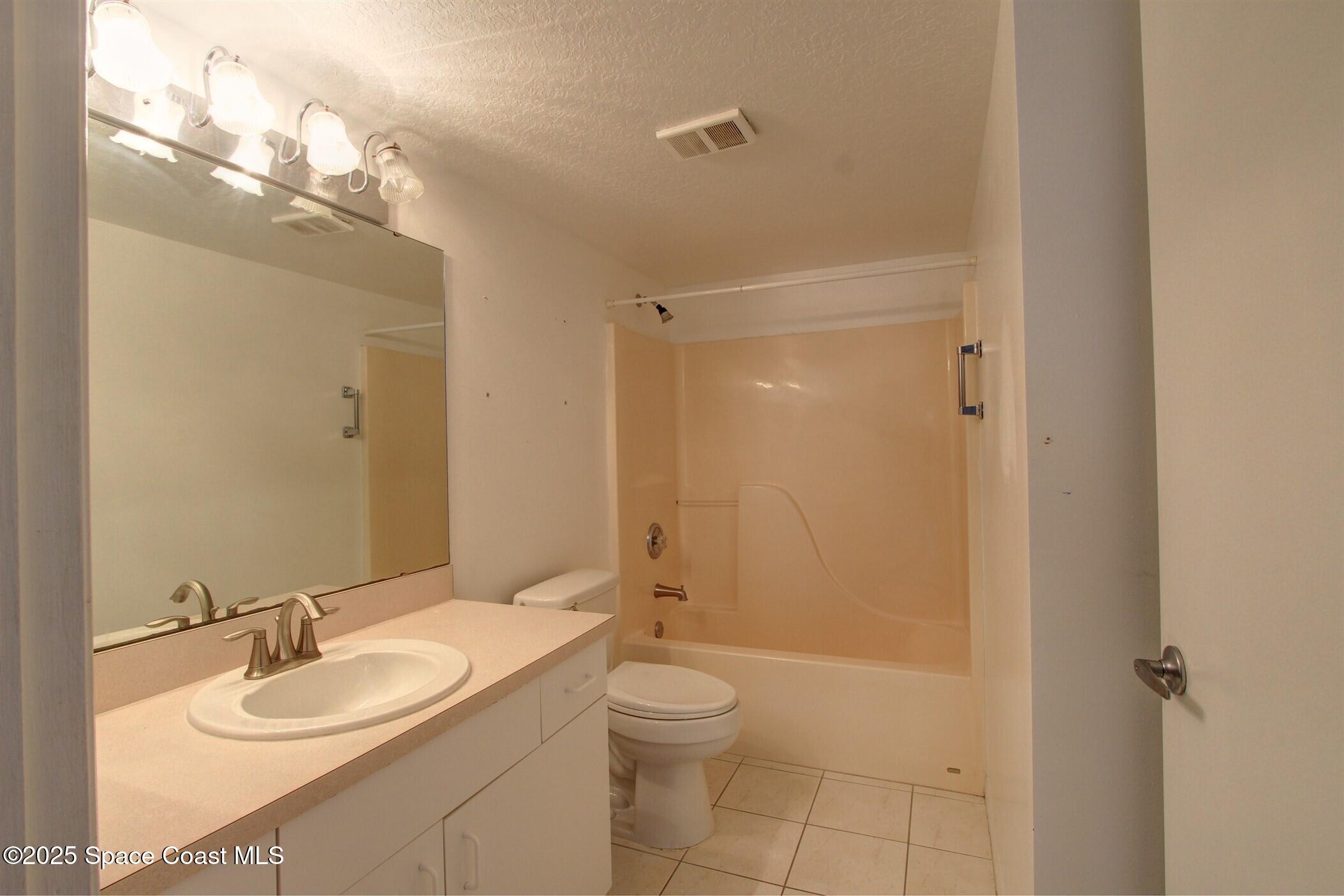 1420 Huntington Lane, Unit 2101 Rockledge, FL 32955 - Photo 31 of 38 a bathroom with a granite countertop sink a toilet a mirror and shower