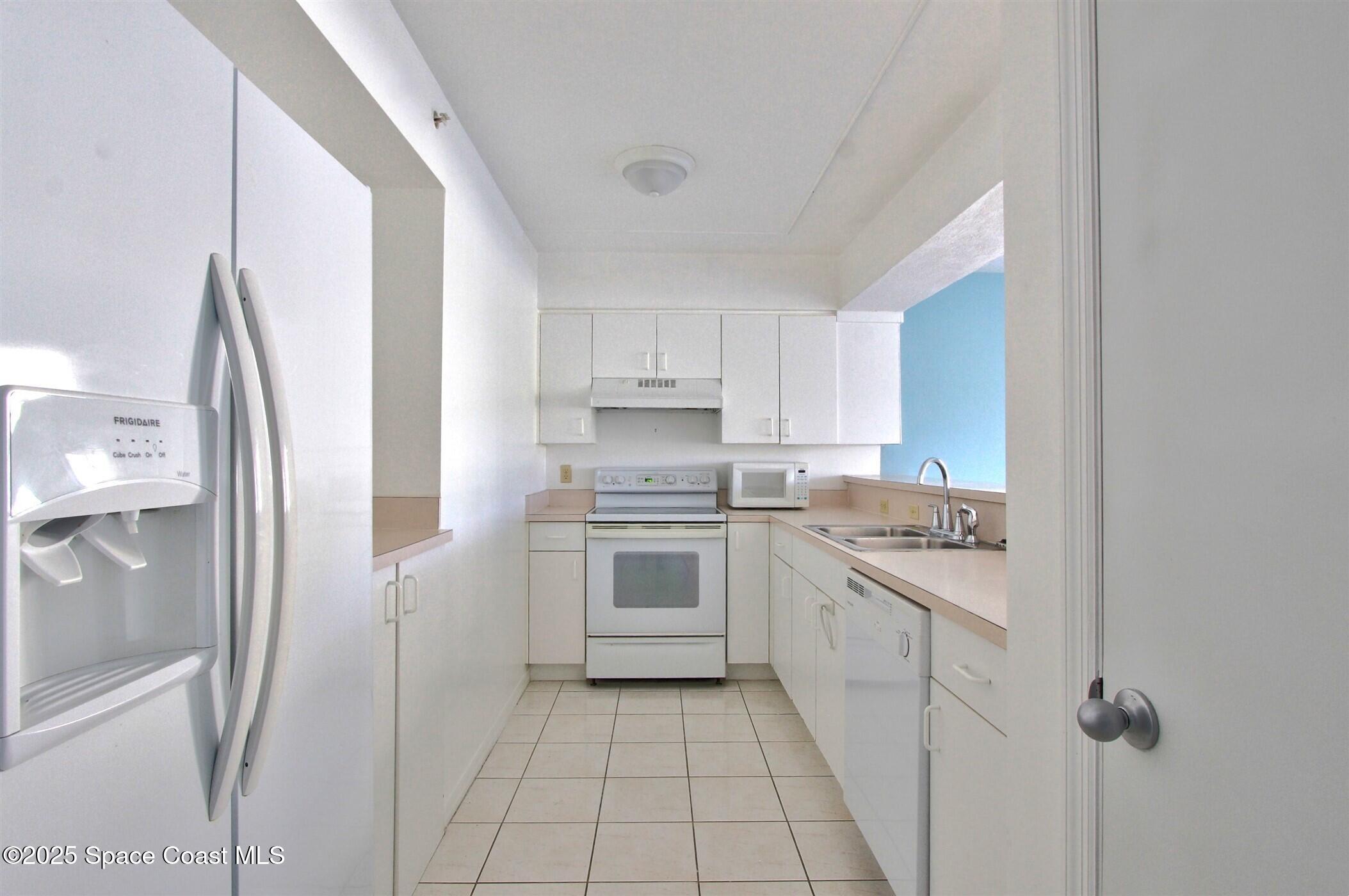 1420 Huntington Lane, Unit 2101 Rockledge, FL 32955 - Photo 10 of 38 a kitchen with a sink a refrigerator and cabinets