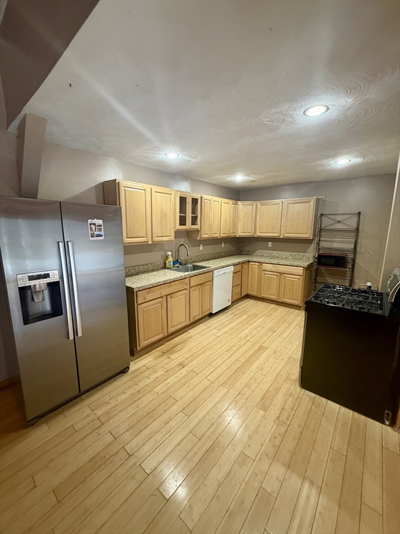 18 Avon Street, Unit B Reading, MA 01867 - Photo 8 of 14 a large kitchen with stainless steel appliances a large counter top a stove a chimney a sink and a refrigerator
