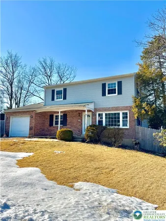 a front view of a house with a yard covered with snow and trees