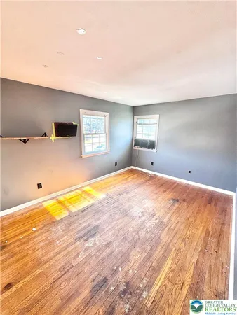 a view of a big room with wooden floor and windows