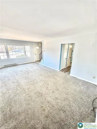 a view of an empty room with wooden floor and kitchen view