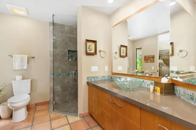 a spacious bathroom with a granite countertop sink a toilet a mirror and shower