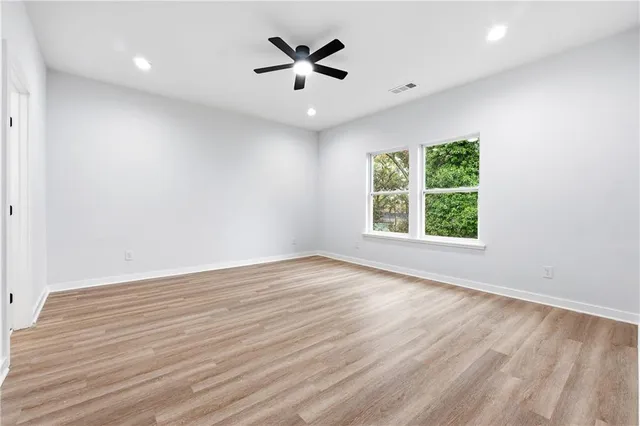 an empty room with wooden floor and windows