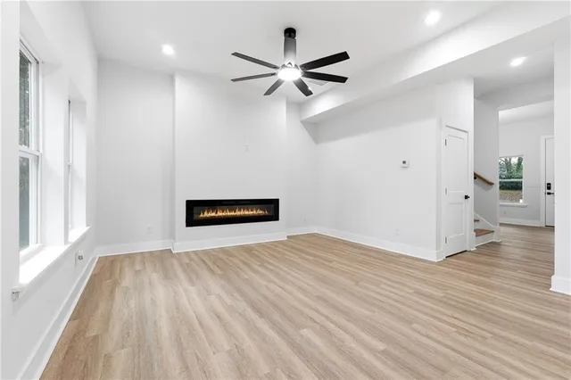 a view of empty room with wooden floor and ceiling fan