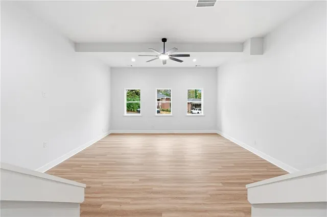 an empty room with windows and ceiling fan