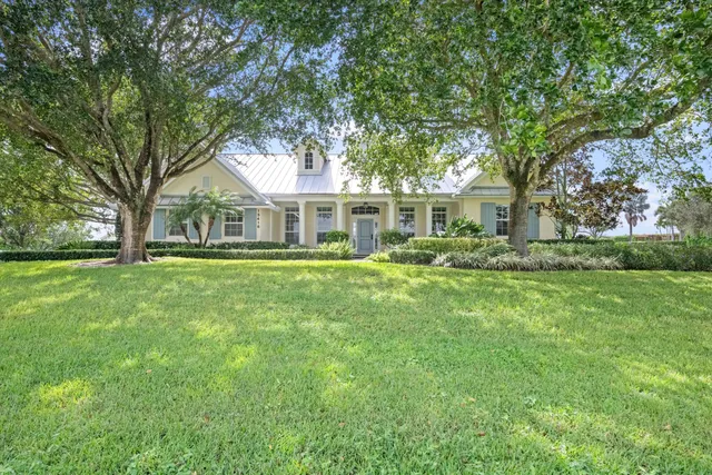 a front view of a house with a garden and trees