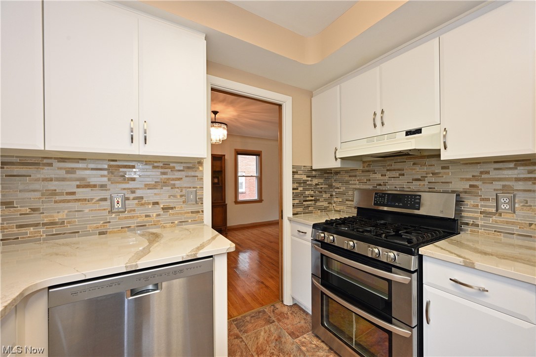 3798 Hillbrook Road Cleveland, OH 44118 - Photo 19 of 34 Kitchen featuring tasteful backsplash, light stone countertops, light tile floors, appliances with stainless steel finishes, and white cabinetry