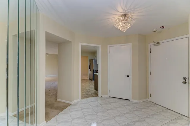 a view of a hallway with a chandelier fan and closet area