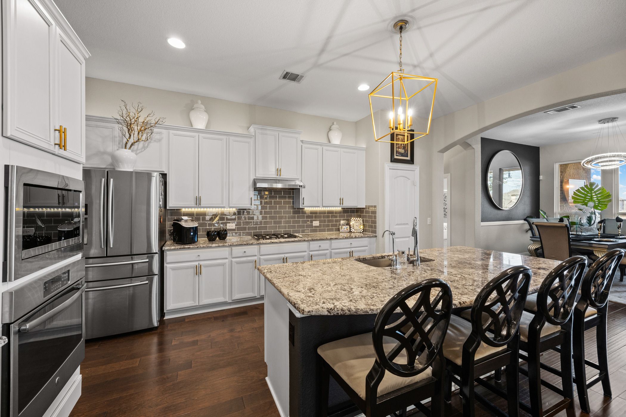 381 Betony Loop Buda, TX 78610 - Photo 3 of 32 a kitchen with granite countertop a table chairs microwave and cabinets