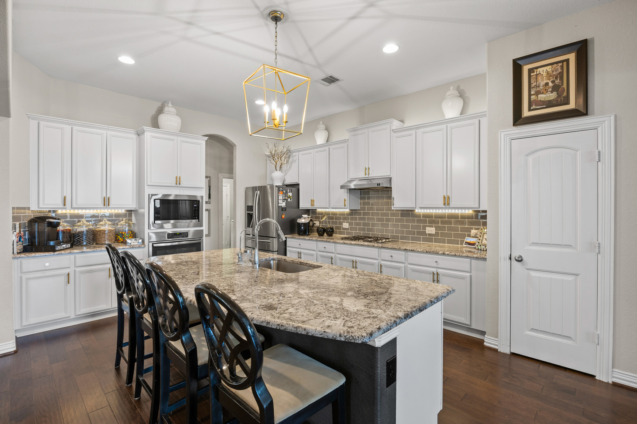 381 Betony Loop Buda, TX 78610 - Photo 5 of 32 a kitchen with stainless steel appliances granite countertop a kitchen island a stove a table and chairs in it