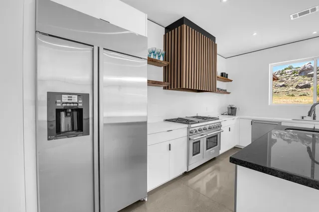 a kitchen with stainless steel appliances granite countertop a sink a stove and a refrigerator