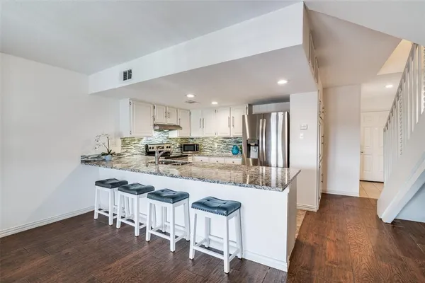 a kitchen with stainless steel appliances kitchen island granite countertop a table and chairs