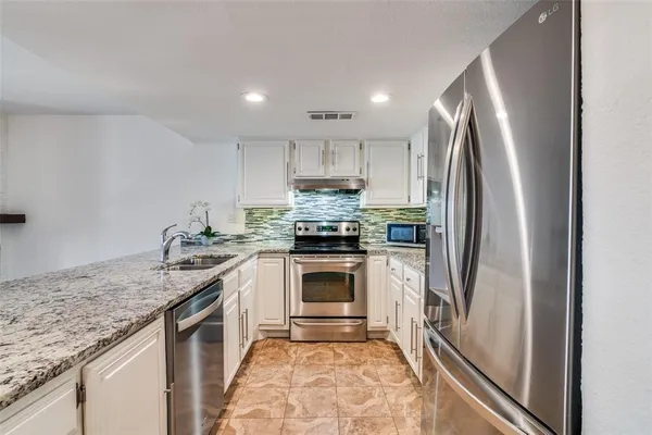 a kitchen with granite countertop a refrigerator stove and sink
