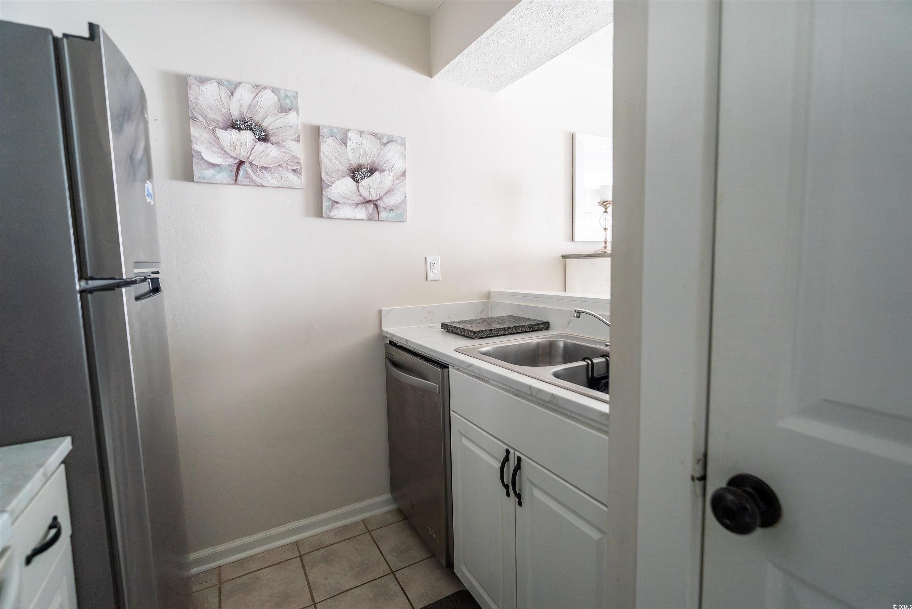 4715 Cobblestone Drive Myrtle Beach, SC 29577 - Photo 4 of 12 Kitchen featuring stainless steel appliances, light countertops, light tile patterned floors, and white cabinets