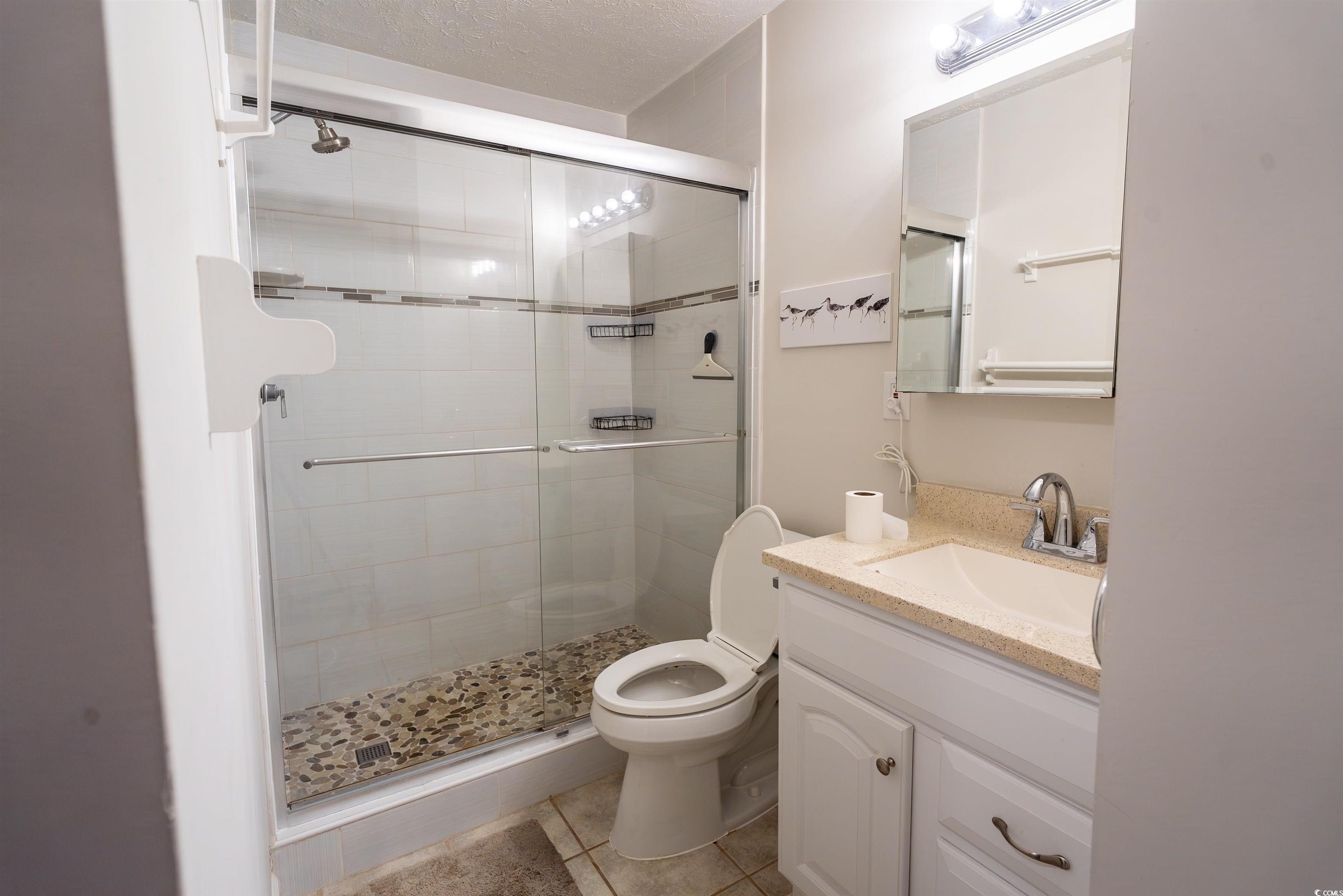 4715 Cobblestone Drive Myrtle Beach, SC 29577 - Photo 10 of 12 Bathroom featuring vanity, a shower stall, light tile patterned floors, and a textured ceiling