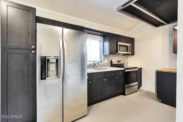 a kitchen with stainless steel appliances granite countertop a refrigerator and a stove top oven