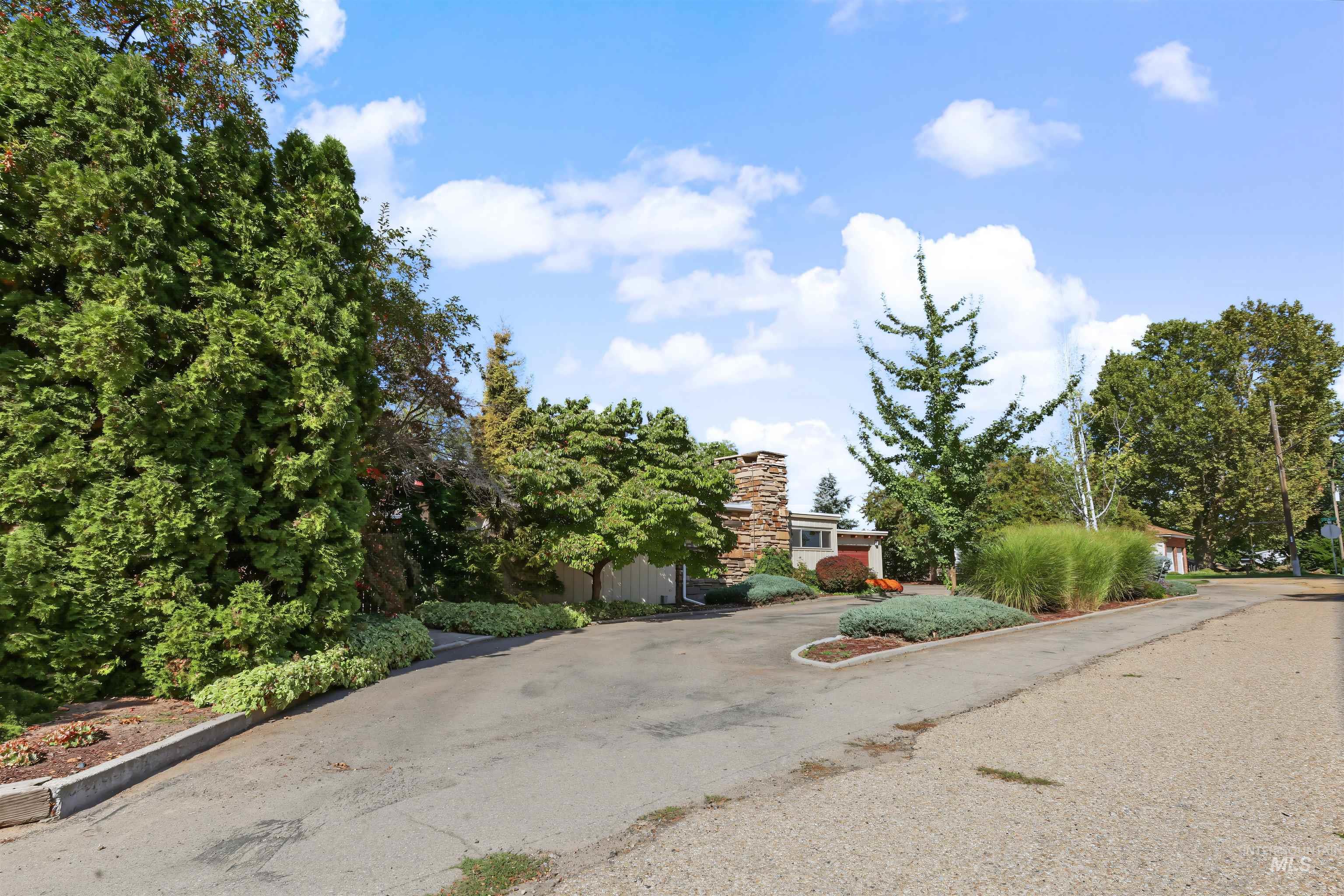 508 East Elm Avenue Parma, ID 83660 - Photo 35 of 50 Stone chimney exterior, mature trees, landscaped shrubbery, paved driveway, established plantings