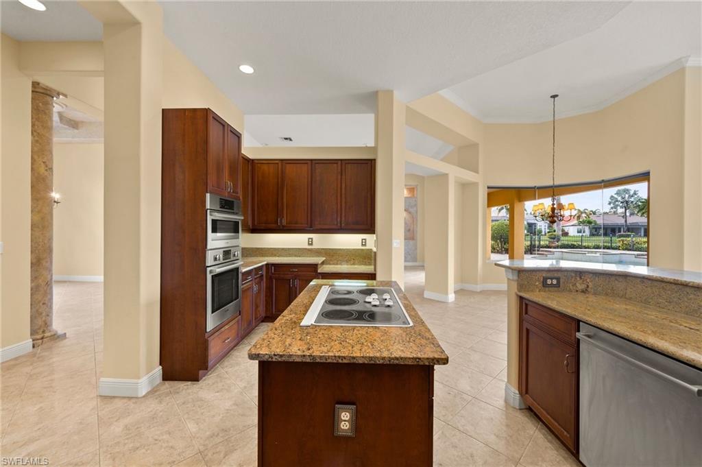 527 Terracina Way Naples, FL 34119 - Photo 21 of 48 a kitchen with stainless steel appliances granite countertop wooden cabinets a stove and a refrigerator