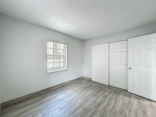 a view of an empty room with wooden floor and a window