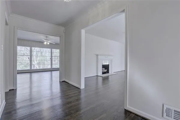 a view of an empty room with wooden floor and a window