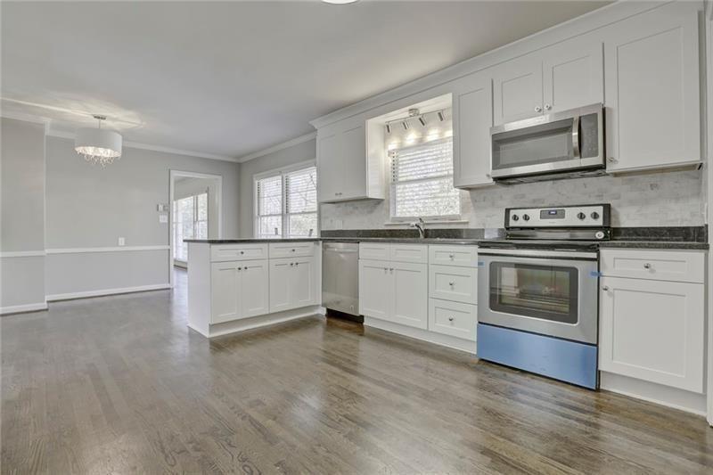 1195 Mt Paran Road Northwest Atlanta, GA 30327 - Photo 7 of 24 a kitchen with stainless steel appliances granite countertop white cabinets a sink a stove a microwave and wooden floors