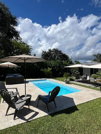 a view of pool with lawn chairs and a yard