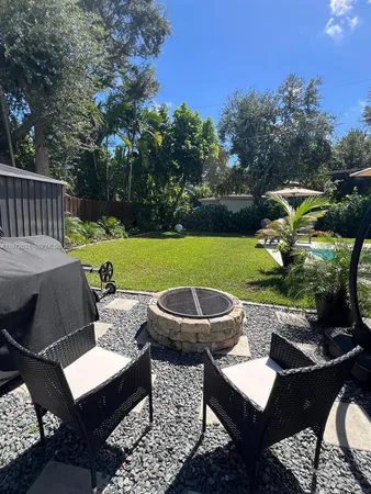 a view of a patio with table and chairs potted plants and a palm tree