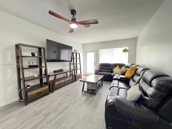a living room with furniture a ceiling fan and a window