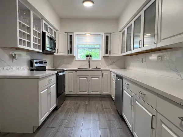 a kitchen with a white cabinets stove and wooden floor