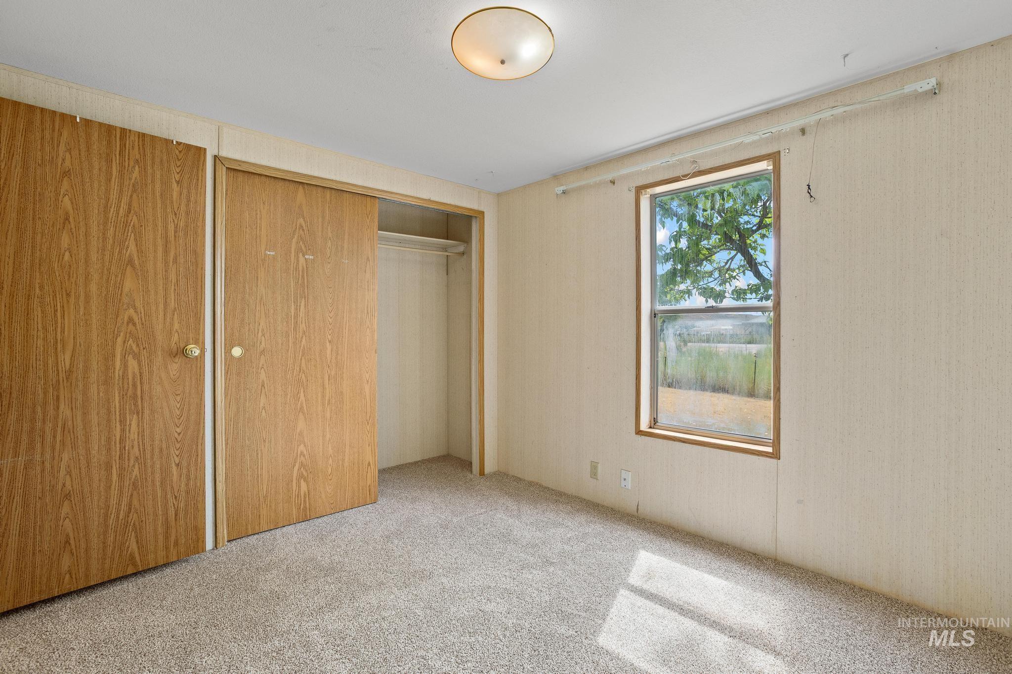 3680 South Mill Road Emmett, ID 83617 - Photo 23 of 38 Carpeted interior space featuring wood-finish closet doors, a single window, and a flush-mount ceiling light fixture